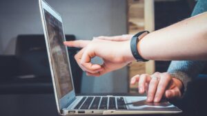 finger pointing at screen on laptop